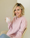 Load image into Gallery viewer, Woman wearing a pink sweatshirt with text, holding a mug, sitting on a chair.- Thread Vision Spotlight, Loverly Grey