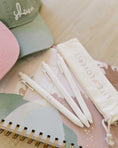 Load image into Gallery viewer, White pens on a notebook with a green cap and white pouch labeled 'LIFE IS LOVE' on a light wooden surface. - Thread Vision Spotlight, Loverly Grey