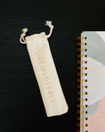 Load image into Gallery viewer, White drawstring pouch with 'LIFE is LOVELY' text next to a spiral-bound notebook on a dark surface. - Thread Vision Spotlight, Life With Loverly
