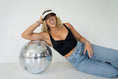 Load image into Gallery viewer, Woman wearing a black tank top and jeans, leaning against a disco ball with a white background - Thread Vision Spotlight, Move Like Morgan