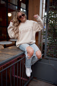 Load image into Gallery viewer, Woman sitting on a railing wearing a beige sweatshirt and ripped jeans. - Thread Vision Spotlight, Move Like Morgan