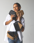 Load image into Gallery viewer, Woman holding black and brown faux leather accessories case and wearing a fanny pack against a plain background - Thread Vision Client Spotlight, RESET by Serena Pitt