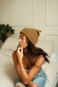 Load image into Gallery viewer, Woman wearing a brown beanie and denim shorts sitting on a couch. - Thread Vision Spotlight, Ignited Apparel