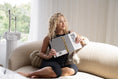 Load image into Gallery viewer, Woman sitting on a couch holding a black and white patterned paper planner in a bright room. - Thread Vision Spotlight, Move Like Morgan