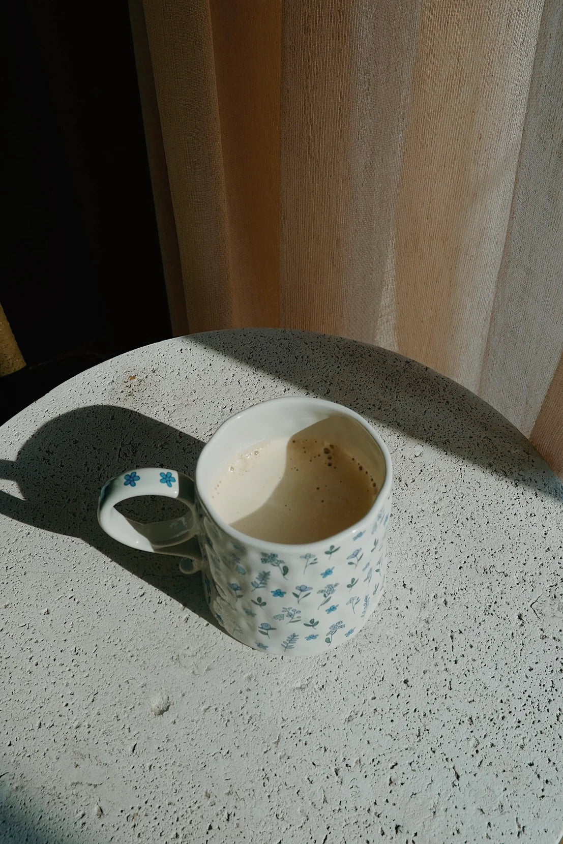 Empty coffee cup with blue floral pattern on a concrete surface - Thread Vision Spotlight, Ignited Apparel