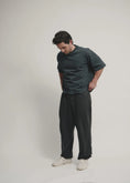 Load image into Gallery viewer, Man wearing a dark green t-shirt and black pants on a plain background - Thread Vision Spotlight, Kinda Handsome
