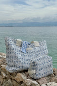 Load image into Gallery viewer, Two patterned bags on rocks with a body of water and sky in the background - Thread Vision Spotlight, Ignited Apparel
