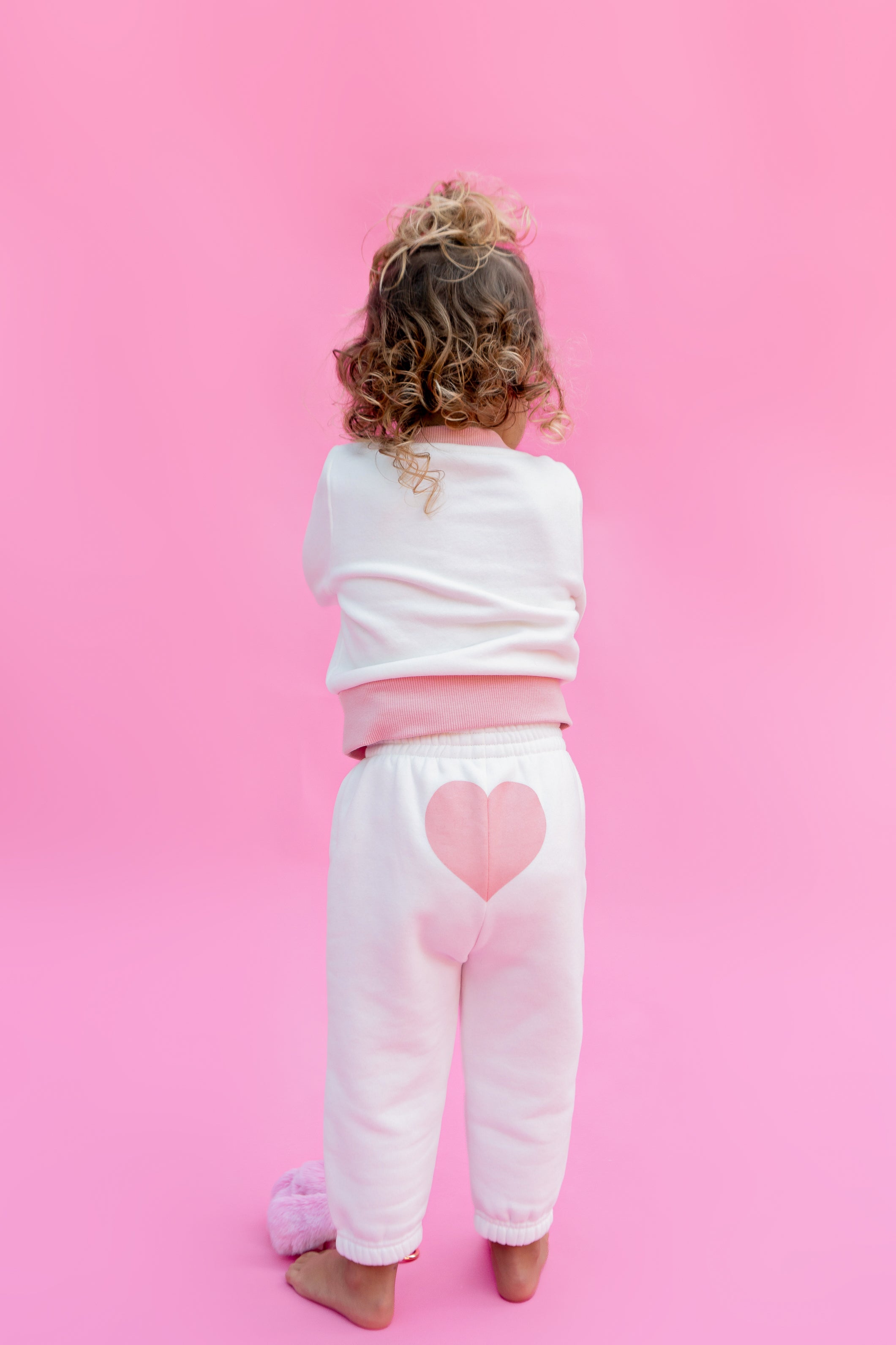 Child wearing a white sweater and sweatpants outfit with pink hearts on a pink background - Thread Vision Spotlight, Rydel