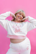 Load image into Gallery viewer, Person wearing a white sweatshirt with pink text on a pink background - Thread Vision Spotlight, Rydel

