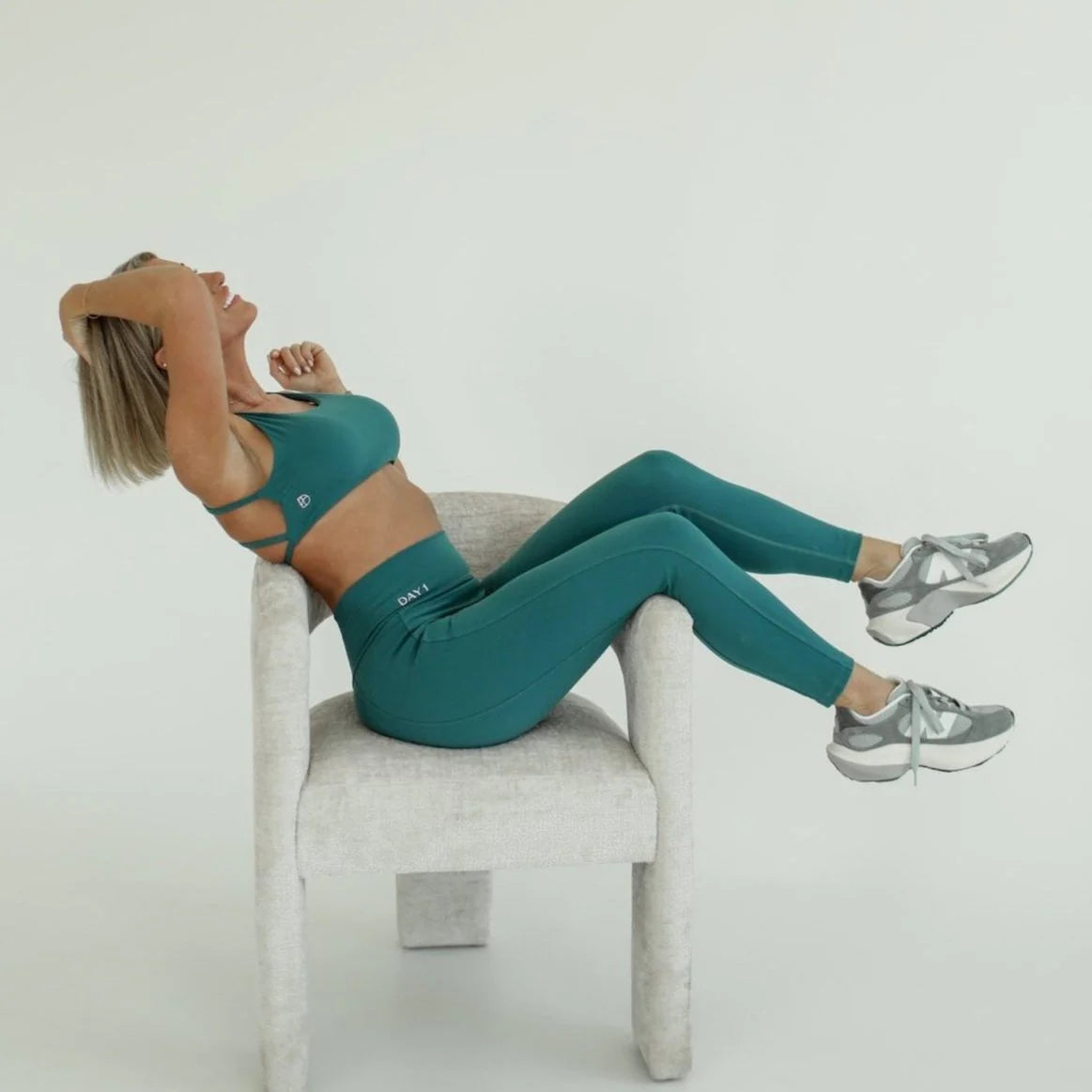 Woman in teal workout outfit sitting on a chair against a white background - Thread Vision Spotlight, Day 1 Fitness, Kaylee Rogers 