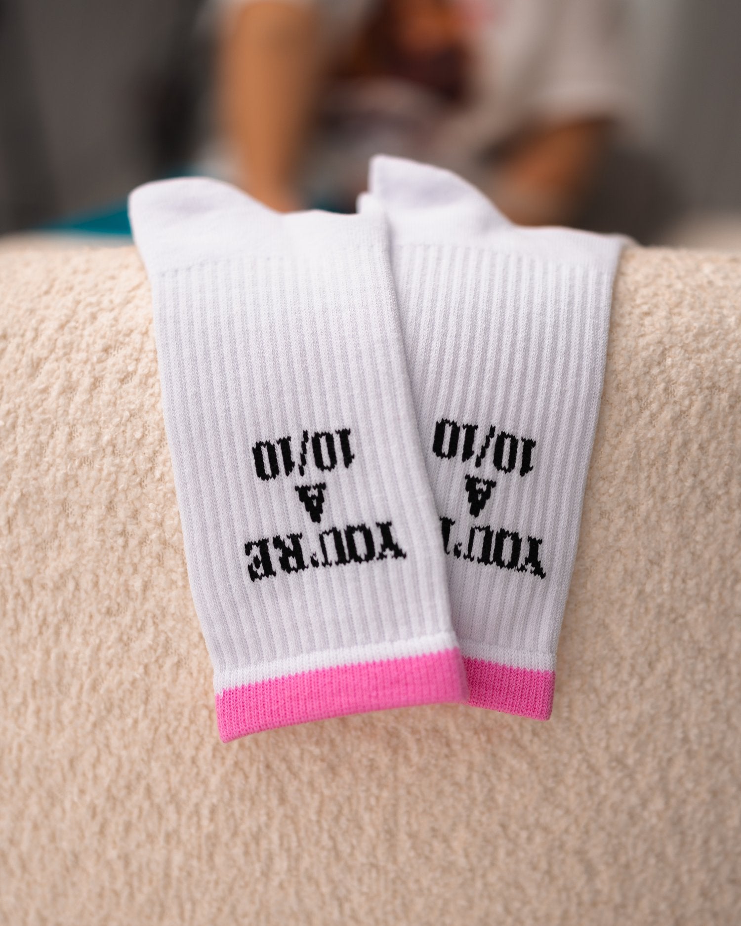 White socks with text and pink accents on a beige surface - Thread Vision Client Spotlight, 10/10 Deanna Giulietti 
