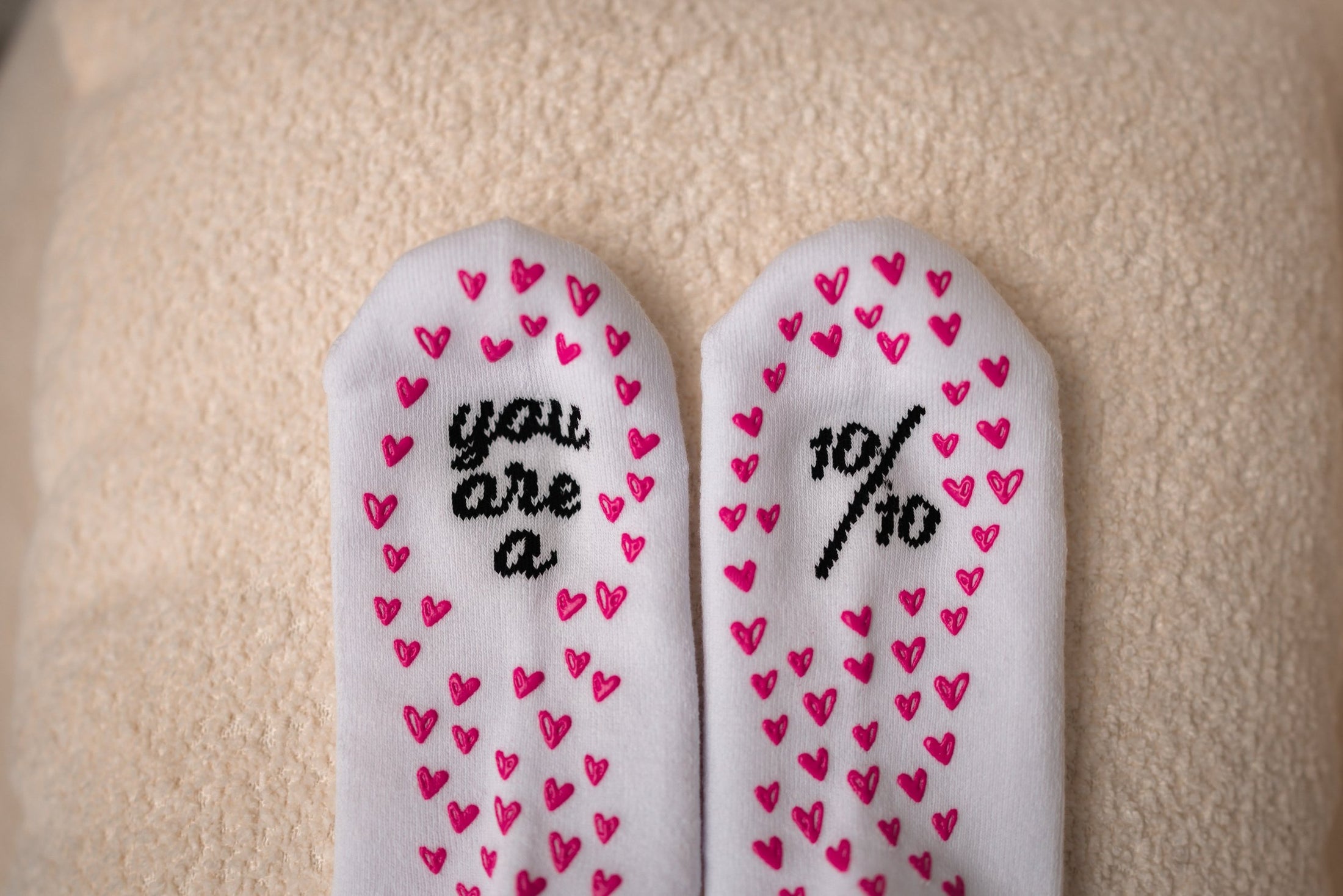 Pair of white insoles with pink heart patterns and text on a beige surface - Thread Vision Client Spotlight, 10/10 Deanna Giulietti 