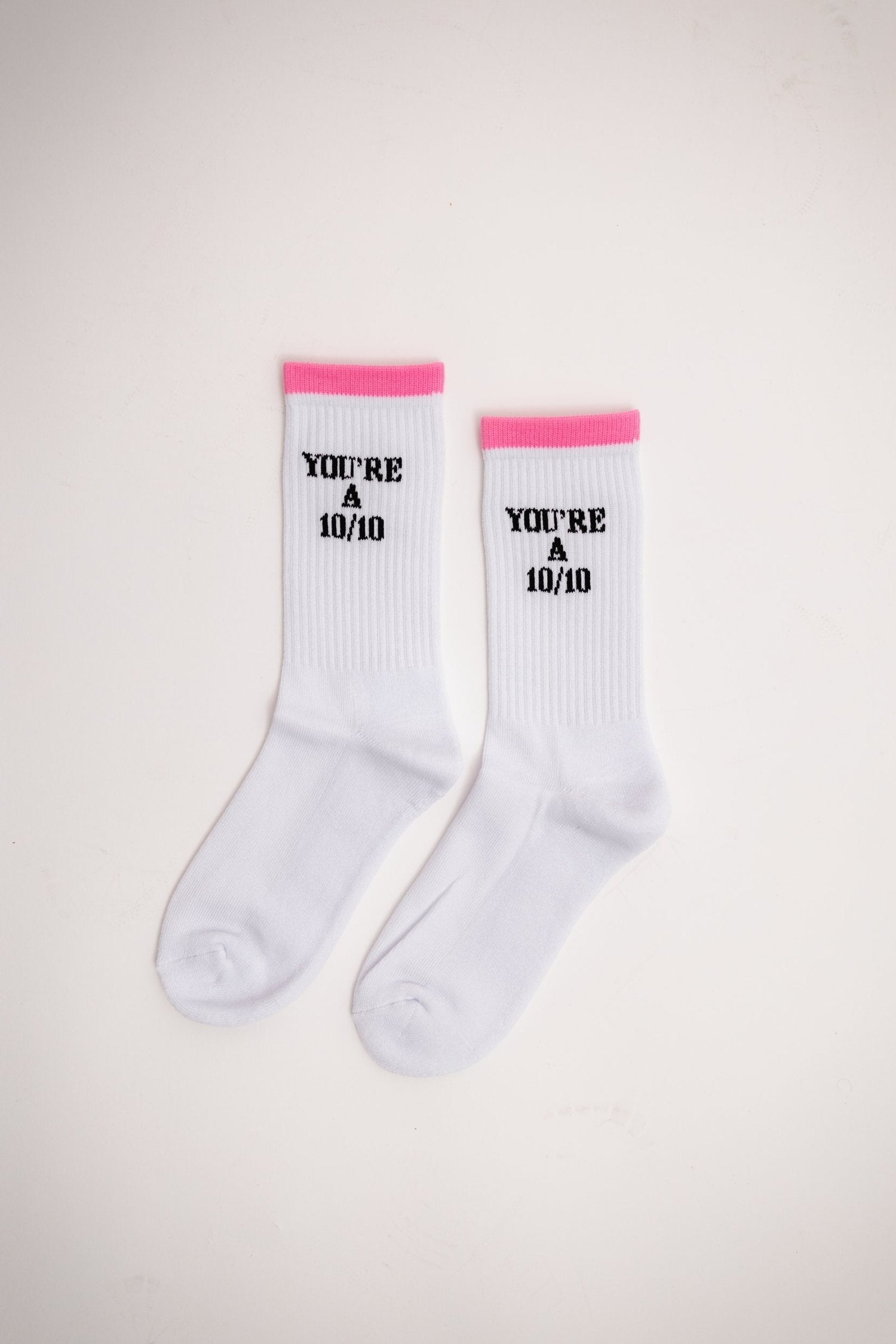 White socks with pink accents and text on a light beige background - Thread Vision Client Spotlight, 10/10 Deanna Giulietti 