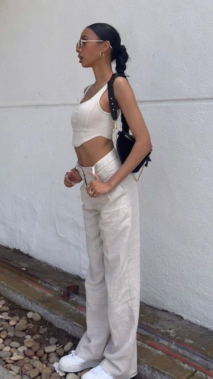 Woman in a white outfit standing against a white wall.  - Thread Vision Client Spotlight, Asha Bailey