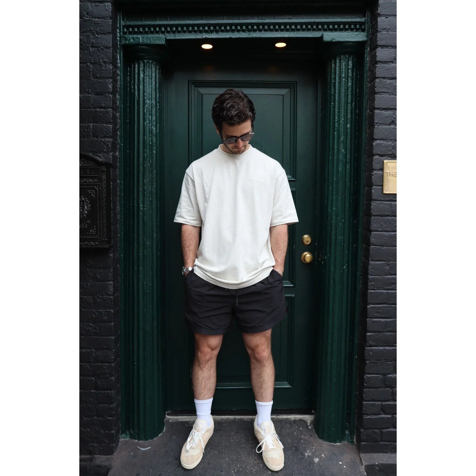 Man standing in front of a dark green door wearing a white t-shirt, black shorts, and white sneakers. - Thread Vision Spotlight, Kinda Handsome