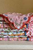 Load image into Gallery viewer, Stack of colorful embroidered fabric pieces on a beige surface with a beige wall background. Thread Vision Client Spotlight, Maude & May by Talia Hubble
