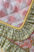 Load image into Gallery viewer, Quilt with ruffled edge and visible brand label, featuring pink, green, and floral patterns. Thread Vision Client Spotlight, Maude & May by Talia Hubble
