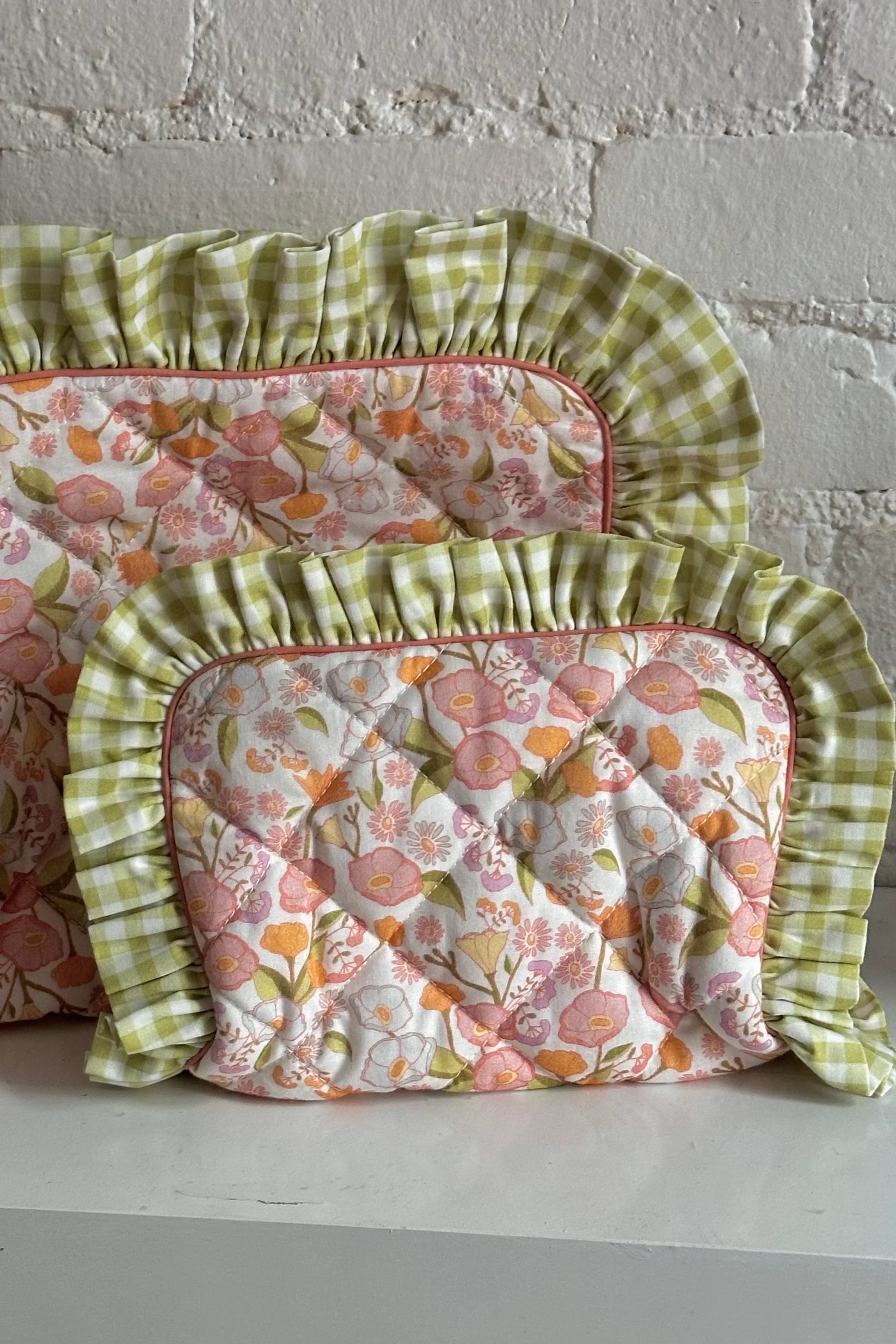 Floral-patterned cushions with green checkered trim on a white surface. Thread Vision Client Spotlight, Maude & May by Talia Hubble