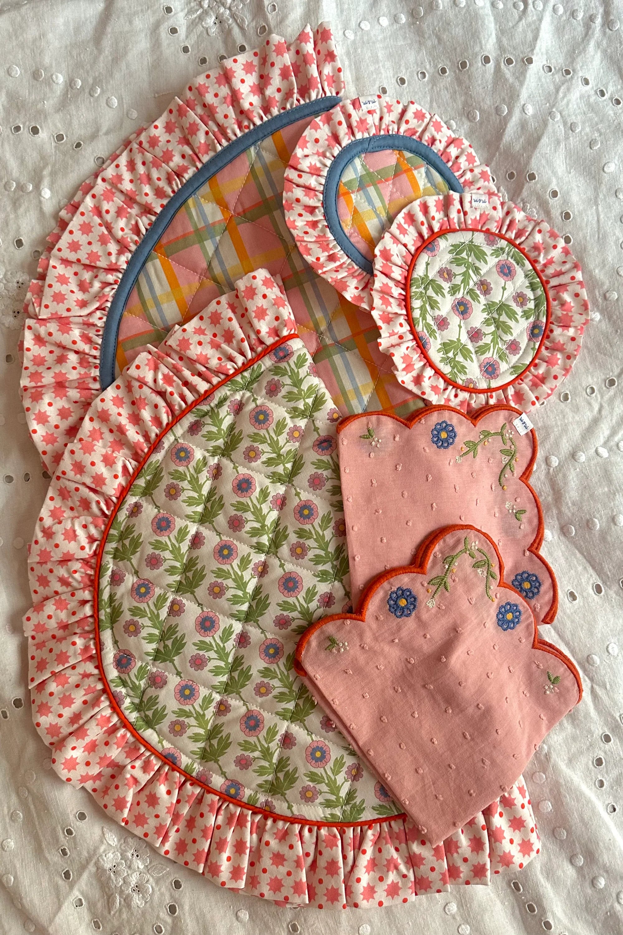 Set of pink floral-patterned oven mitts and pot holders on a textured white background - Thread Vision Client Spotlight, Maude& May by Talia Hubble
