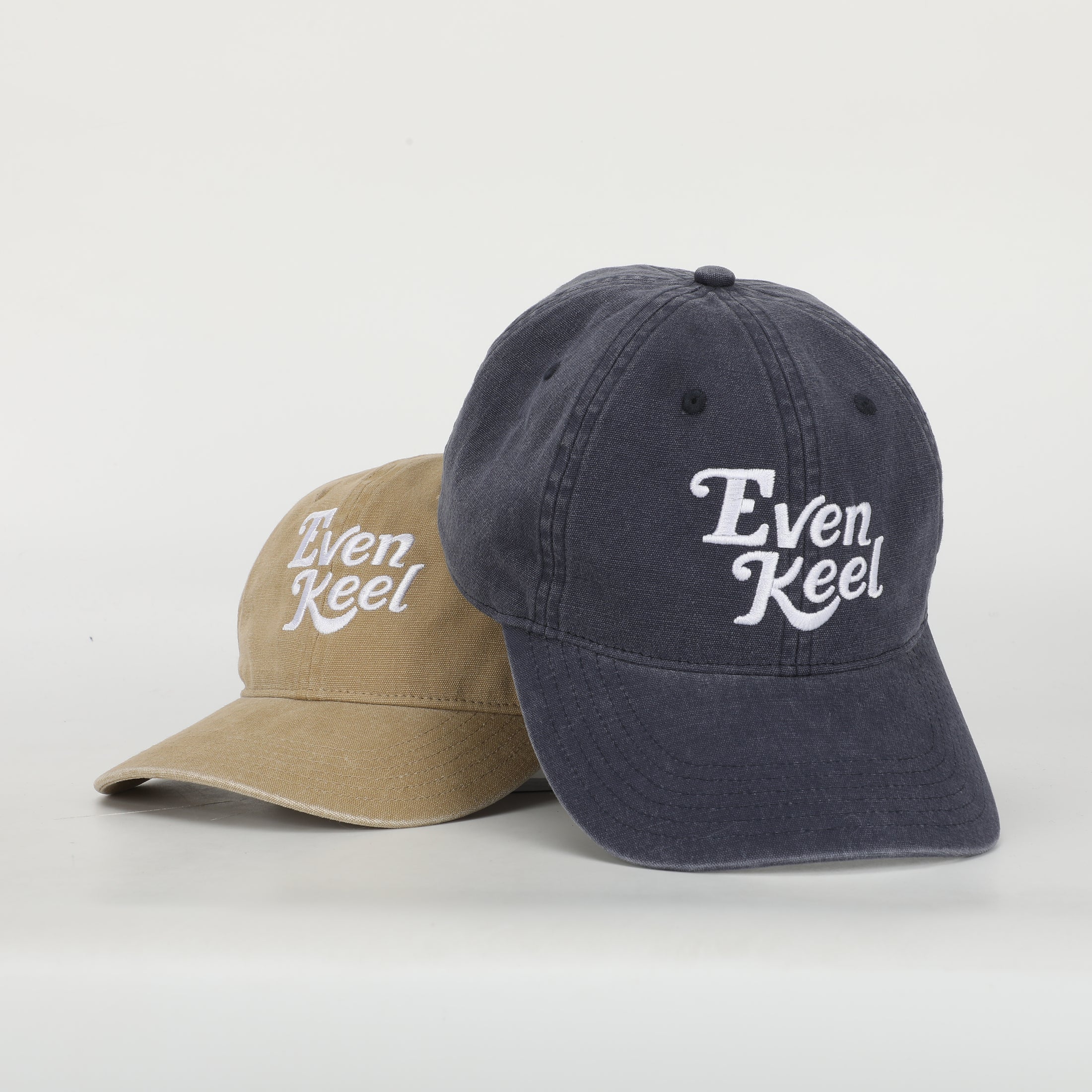 Two baseball caps, one beige and one navy, with 'Even Keel' logo on a white background - Thread Vision Client Spotlight