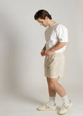Load image into Gallery viewer, Man wearing a white t-shirt and beige shorts against a plain background - Thread Vision Spotlight, Kinda Handsome
