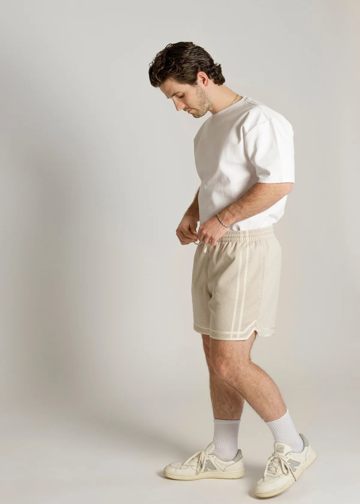 Man wearing a white t-shirt and beige shorts against a plain background - Thread Vision Spotlight, Kinda Handsome