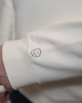Load image into Gallery viewer, Close-up of a white shirt cuff with a small embroidered design. - Thread Vision Spotlight, Loe Hayley
