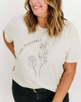 Load image into Gallery viewer, Woman wearing a white t-shirt with floral design and text on a plain background - Thread Vision Spotlight, Loverly Grey
