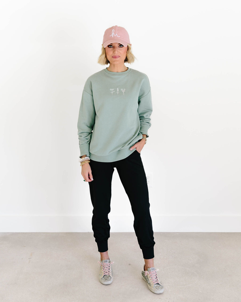 Person wearing a light green sweatshirt with 'FIV' logo, black pants, pink cap, and sneakers on a white background - Thread Vision Spotlight, Loverly Grey