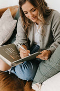 Load image into Gallery viewer, Woman sitting on a couch writing in a notebook - Thread Vision Spotlight, PCOS Planner
