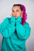 Load image into Gallery viewer, Person wearing a teal sweatshirt with pink hair against a plain background - Thread Vision Client Spotlight, 10/10 Deanna Giulietti 
