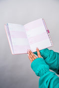 Load image into Gallery viewer, Hand holding an open planner with a teal sleeve on a gray background - Thread Vision Client Spotlight, 10/10 Deanna Giulietti 
