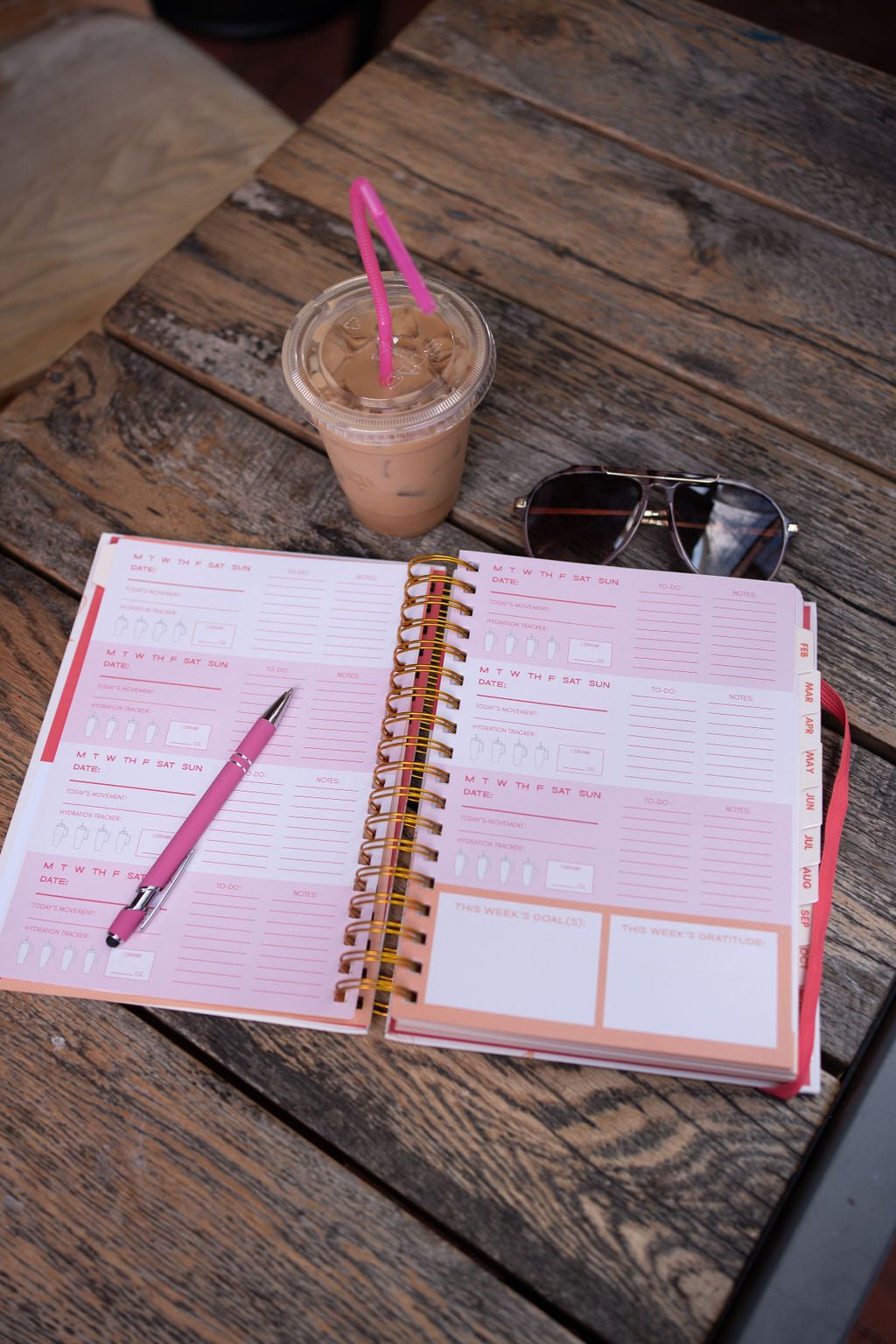 Open planner with pink pen, iced coffee, and sunglasses on a wooden table - Thread Vision Spotlight, Move Like Morgan
