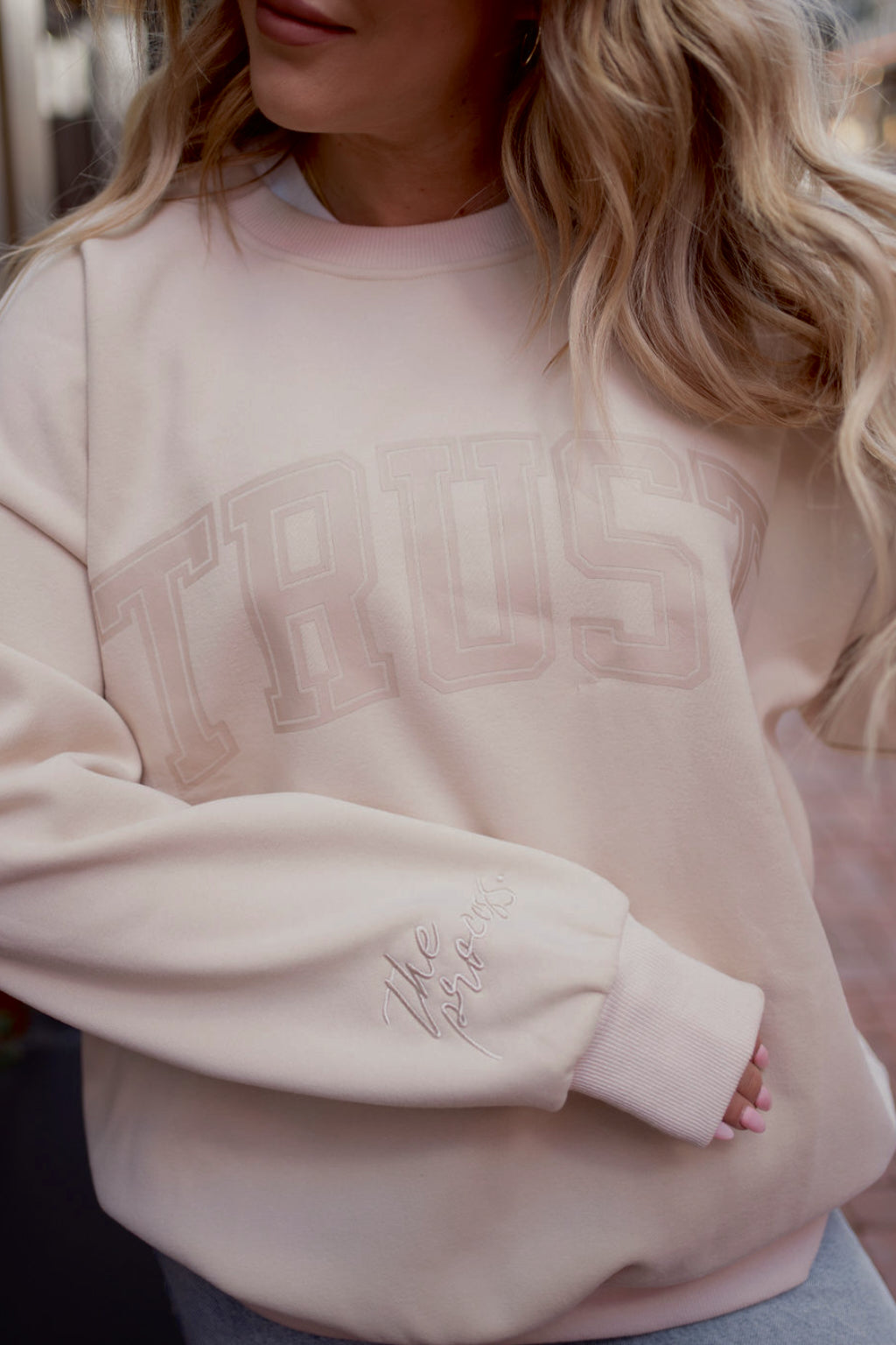 Beige sweatshirt with 'TRUST' text worn by a person with blonde hair. - Thread Vision Spotlight, Move Like Morgan