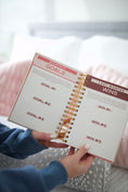 Load image into Gallery viewer, Person holding a spiral-bound notebook with goal-setting pages. - Thread Vision Spotlight, Move Like Morgan
