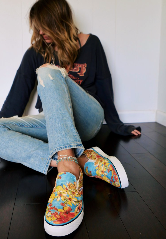 Person wearing colorful floral sneakers sitting on a dark wooden floor. - Thread Vision Client Spotlight, Goldfish Kiss
