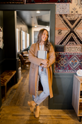 Load image into Gallery viewer, Woman in a long coat holding a paper planner in a room with patterned rugs and wooden floors. - Thread Vision Client Spotlight, Skinny Hangover
