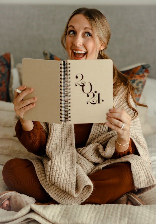 Woman holding a notebook with '2021' on it, sitting on a bed. - Thread Vision Client Spotlight, Skinny Hangover