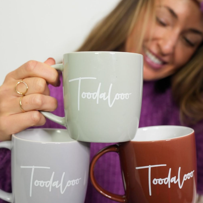 Person holding a 'Toodaloo' mug with two other mugs stacked behind -  - Thread Vision, Client Loe Haley