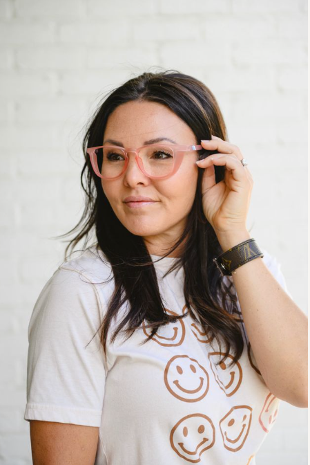 Woman wearing pink glasses and a white t-shirt with smiley face patterns against a light background  - Thread Vision, Client Remington Avenue