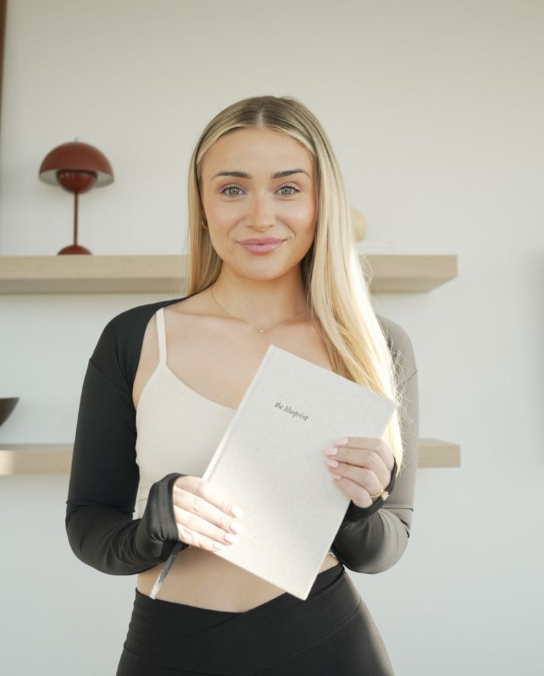 Woman holding a white notebook with a blurred background  - Thread Vision, Client, HMBDY