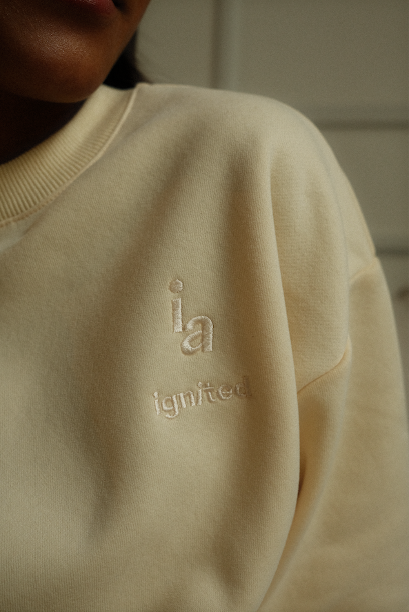 Beige sweatshirt with 'ia ignited' embroidery on a neutral background - Thread Vision Spotlight, Ignited Apparel