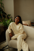 Load image into Gallery viewer, Woman in a white outfit sitting on a white chair in a room with plants. - Thread Vision Spotlight, Ignited Apparel
