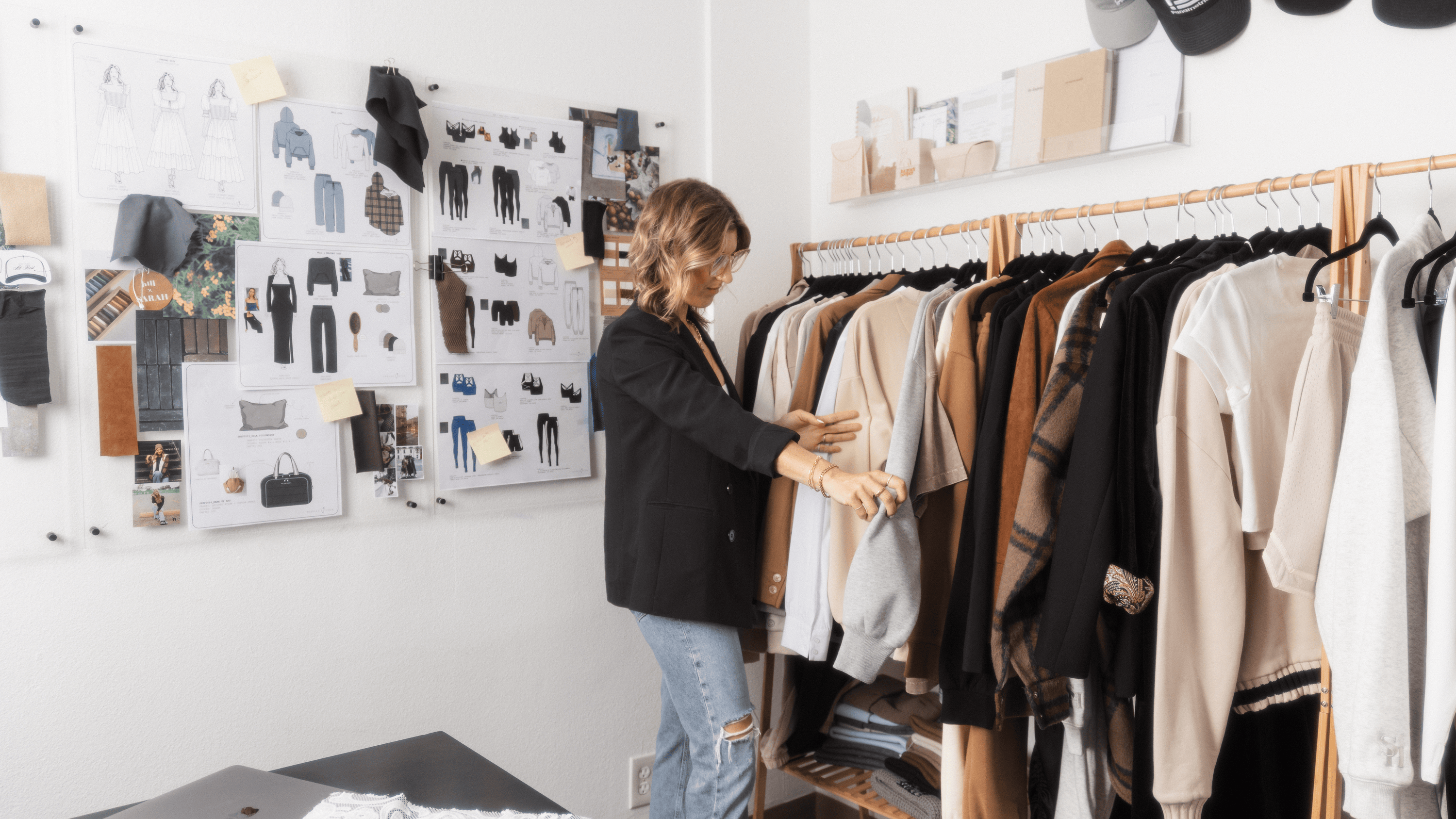Person in a clothing store looking at racks of clothes with design boards on the wall. - Thread Vision Branded Photo