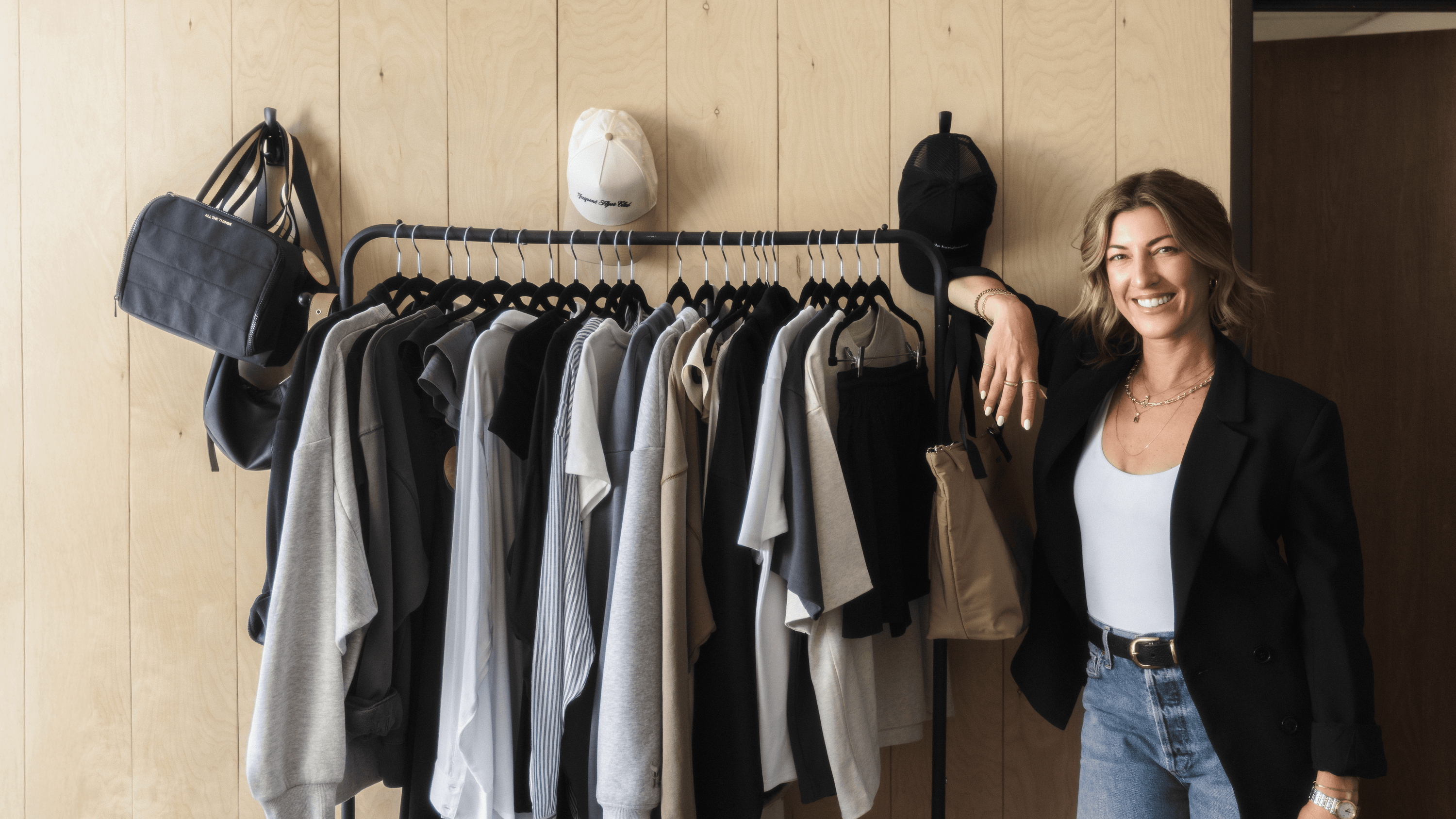 Woman standing next to a rack of clothes in a clothing store. - - Thread Vision Branded Photo 