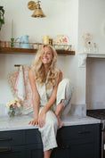 Load image into Gallery viewer, Woman sitting on a kitchen counter with a smile, surrounded by kitchen decor. - Thread Vision Client Spotlight, Maude & May by Talia Hubble
