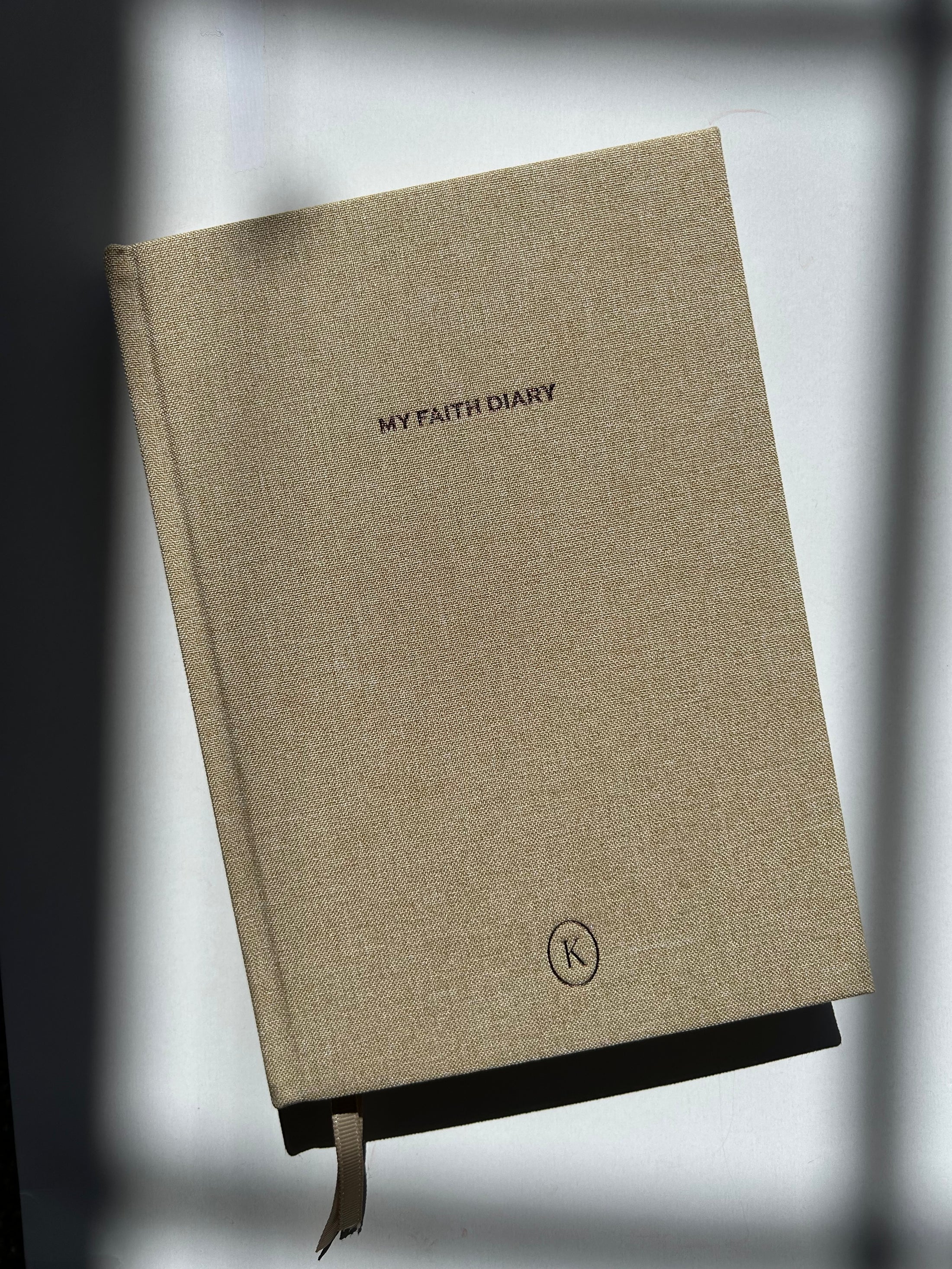 Beige diary with text and logo on a gray background - - Thread Vision Client Spotlight, Karina Faith Diaries