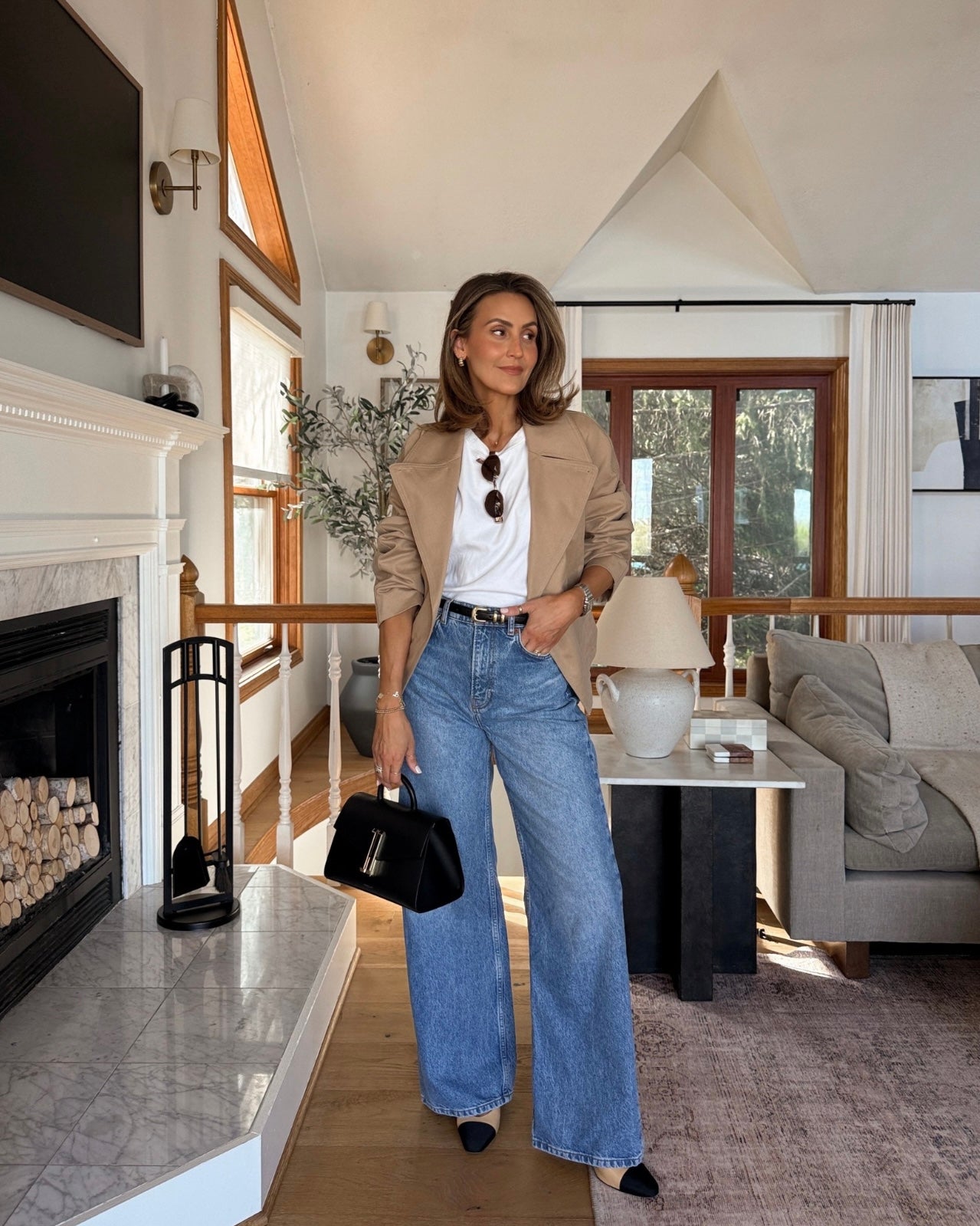 Woman in a living room wearing a beige jacket, white shirt, blue jeans, and black shoes. - Thread Vision Client Spotlight, Karina Faith Diaries