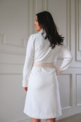 Load image into Gallery viewer, Woman wearing a white bathrobe against a white paneled wall. - Thread Vision Spotlight, Remington Avenue
