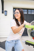 Load image into Gallery viewer, Woman using a saw in front of a house with a smiley face shirt- Thread Vision Spotlight, Remington Avenue
